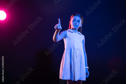 Using technologies. Determined dark-haired girl pressing an imaginary button and wearing a lovely dress