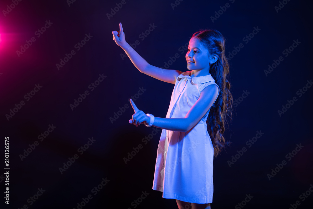 So pleased. Beautiful dark-haired girl pressing imaginary buttons and wearing a lovely dress
