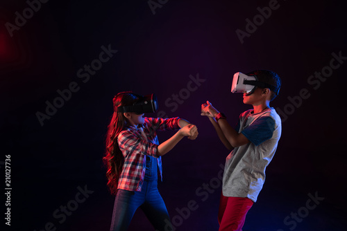 Great game. Content little girl and a boy wearing VR headsets and playing and smiling