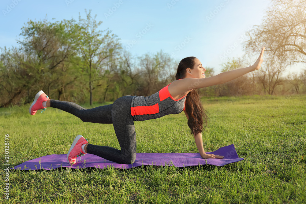 Fototapeta premium Sporty young woman practicing yoga in park