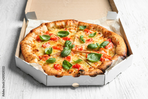 Carton box with delicious pizza Margherita on wooden background photo