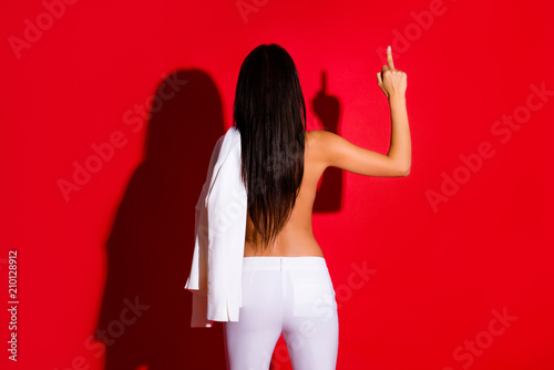 Rear view portrait of slender fit girl with long hair having booty buttocks gesturing fuck off sign with middle finger isolated on bright red background. My rules my life concept