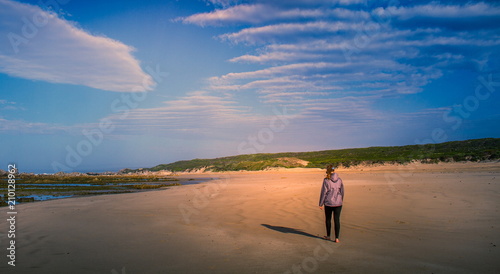 A young girl walks on an empty beach