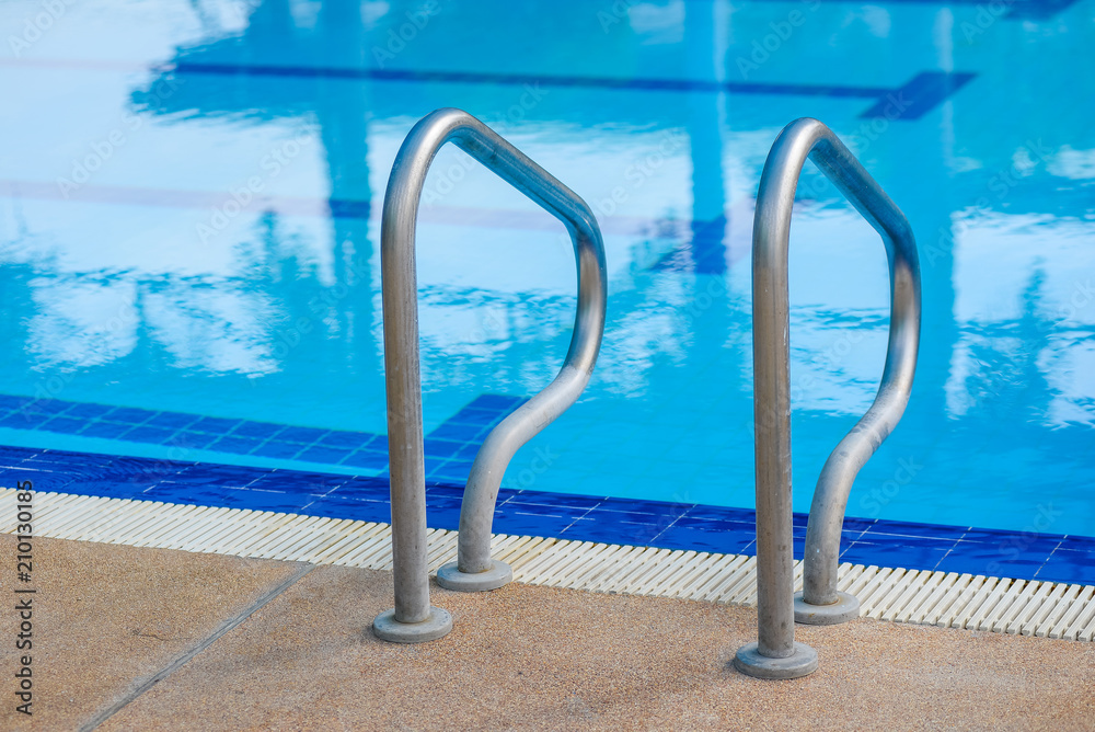 Stainless steel ladder in a blue turquoise swimming pool.