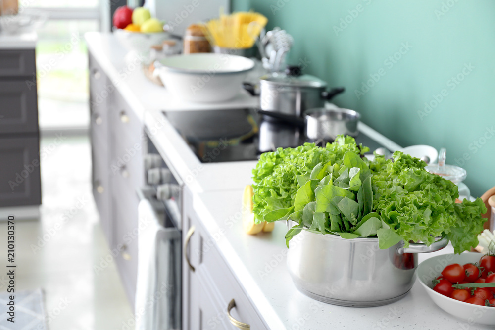 Saucepan with lettuce and sorrel on table in modern kitchen Saucepan with lettuce and sorrel on table in modern kitchen