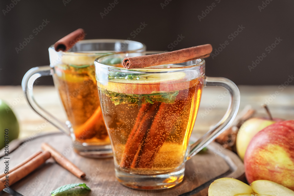 Tasty apple drink with cinnamon in glass cups on wooden board Tasty apple drink with cinnamon in glass cups on wooden board
