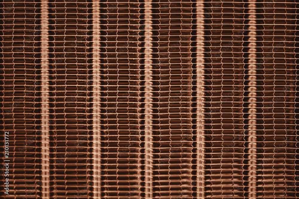 Detailed texture of engine water cooling radiator with vertical lines. Background image of orange automobile part with copy space close up. Detailed texture of engine water cooling radiator with vertical lines. Background image of orange automobile part with copy space close up.