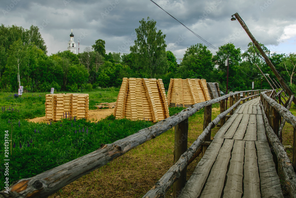 Wooden bridge across river and white church on background, Russia Wooden bridge across river and white church on background, Russia