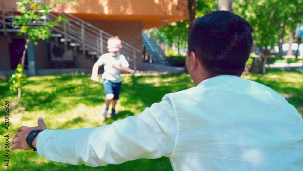 Boy running to his father's arms and hug him, A happy child meets his father near the house