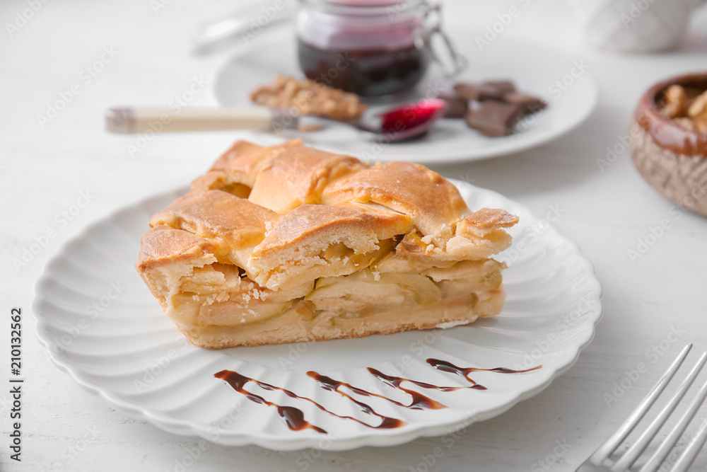 Plate with piece of delicious apple pie on wooden table