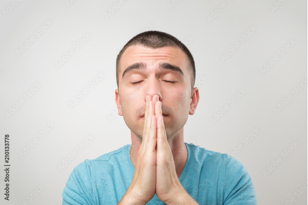 Closeup portrait of desperate young man in blue shirt showing clasped hands,asking for help or excuse. Closeup portrait of desperate young man in blue shirt showing clasped hands,asking for help or excuse.