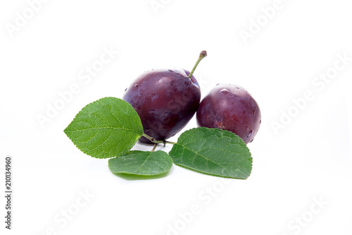 Group of ripe plums with leaf isolated on a white background.