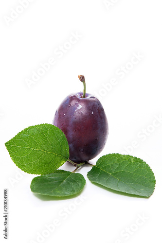 Ripe plum with water drops and green leaf  isolated on white background..
