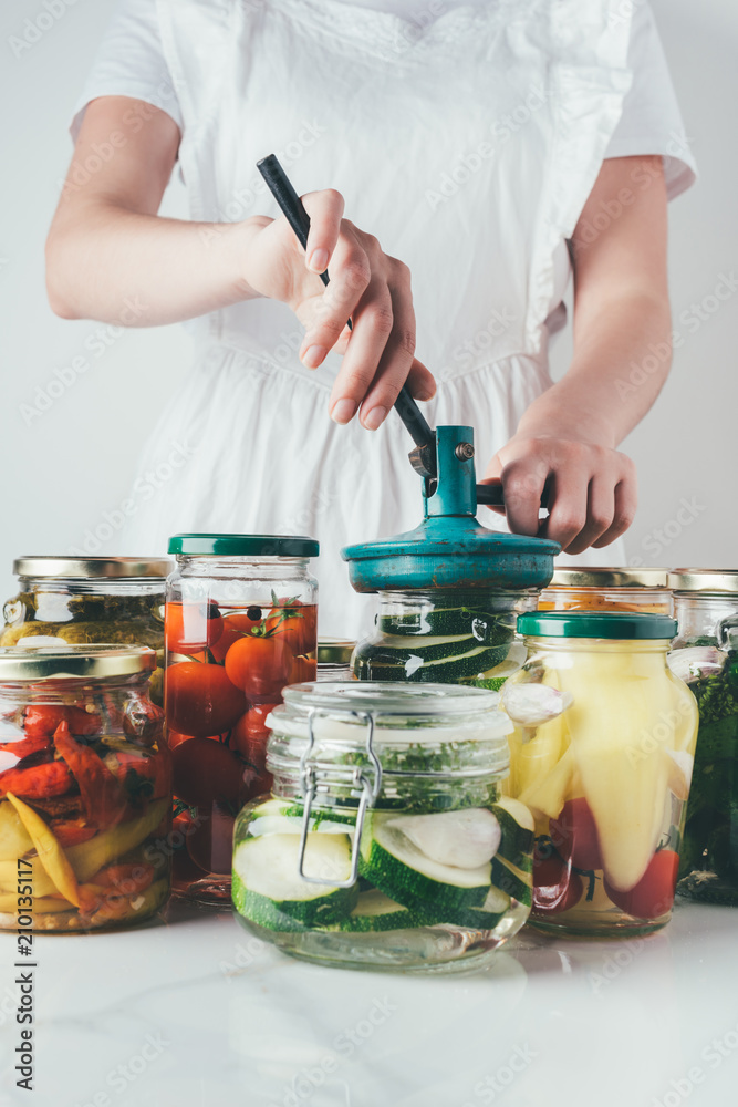 cropped image of woman preparing preserved vegetables on table at kitchen cropped image of woman preparing preserved vegetables on table at kitchen