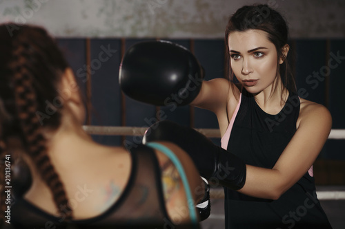 Fit slim young beautiful brunette women boxing in sportswear. Dark dim light. Toned image