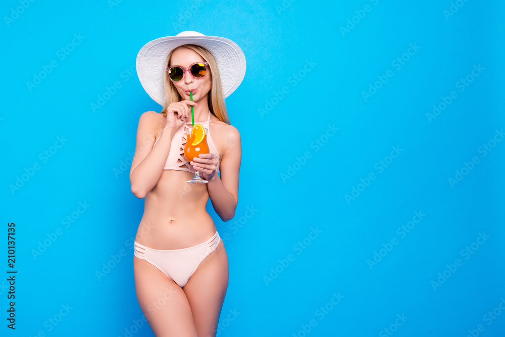 Portrait with copysapce empty place of stunning lady with perfect figure in pink two pieces swimsuit drinking sweet tasty cocktail isolated on bright blue background - obrazy, fototapety, plakaty 