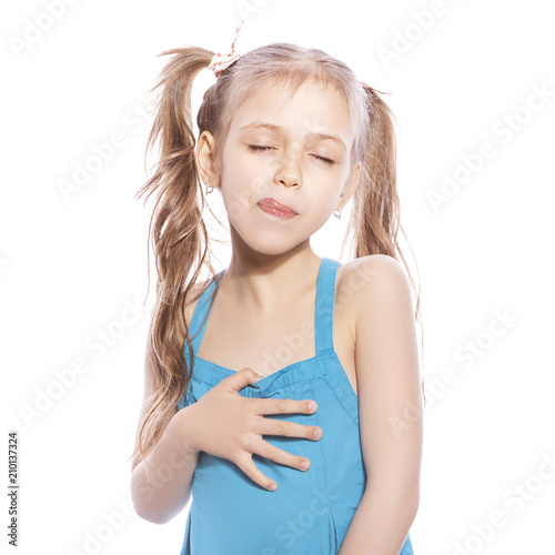 Young seven years old girl in blue dress on a white isolated background. Delightful, joyful emotions on her face, makes yummy, hungry gersture with her hands and face, licking her lips with tongue
