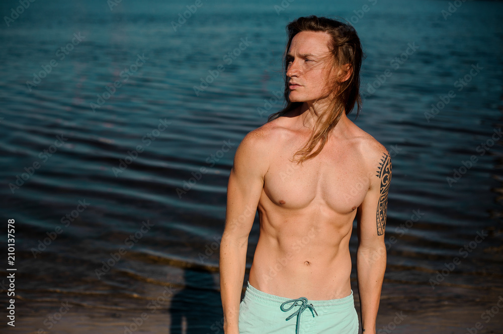 Portrait of a handsome young man standing on the background of blue water Portrait of a handsome young man standing on the background of blue water