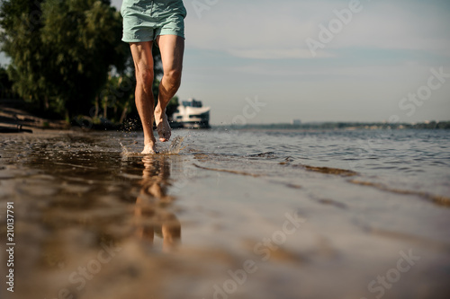 Muscular male feet running along the river bank © fesenko