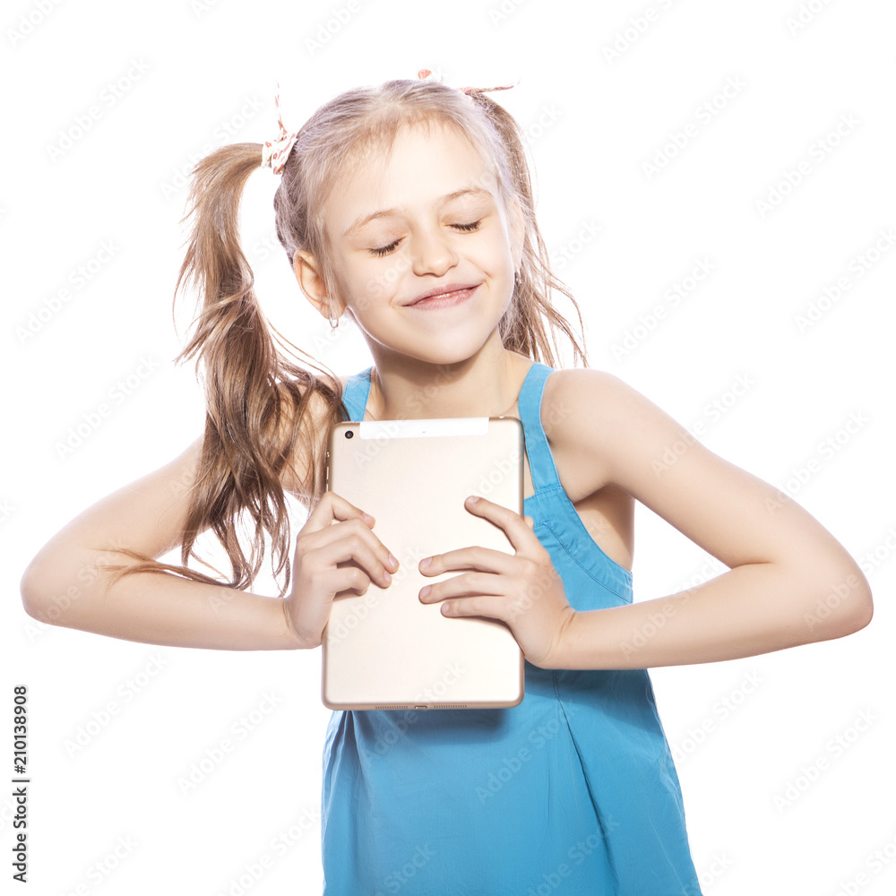 Young seven years old brunette girl in blue dress on a white isolated background. She holds tablet as a present, happiness and joy emotions on her face Young seven years old brunette girl in blue dress on a white isolated background. She holds tablet as a present, happiness and joy emotions on her face