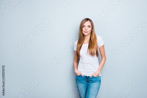 Portrait with copyspace empty place of sexy nice girl in white t-shirt holding two hand in pocket of pants isolated on grey background looking at camera