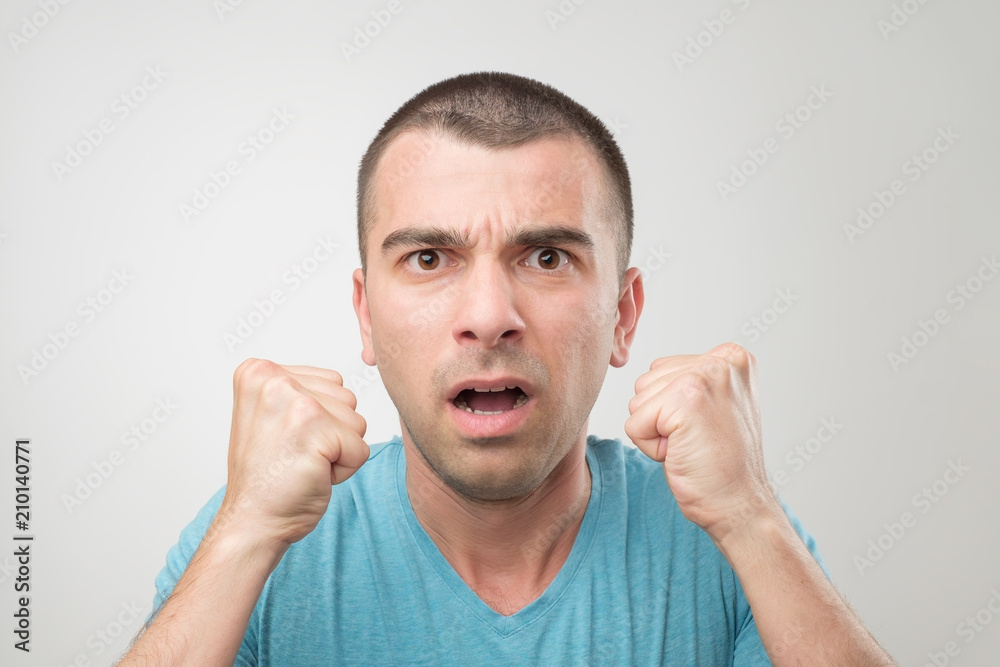 young hispanic man in blue shirt celebrating victory of his team over gray background young hispanic man in blue shirt celebrating victory of his team over gray background