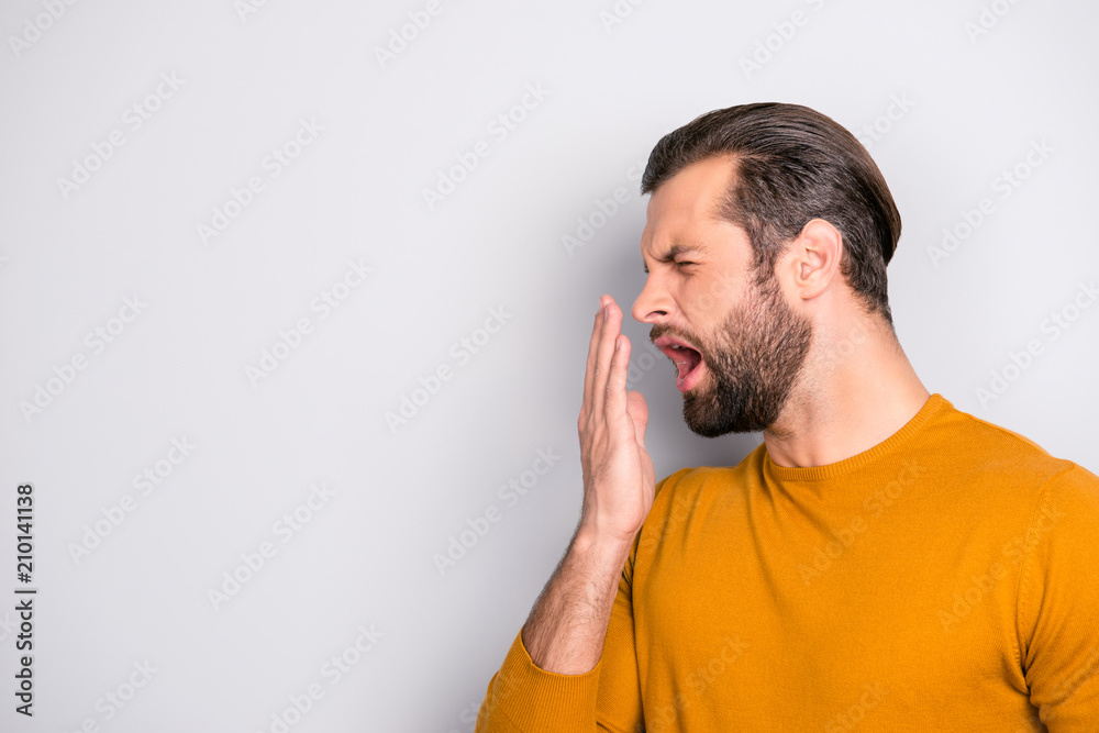 Side profile half-faced portrait of tired sleepy bored handsome bearded unhappy with trendy hairdo guy yawning covering mouth with hand isolated on gray background copy-space Side profile half-faced portrait of tired sleepy bored handsome bearded unhappy with trendy hairdo guy yawning covering mouth with hand isolated on gray background copy-space