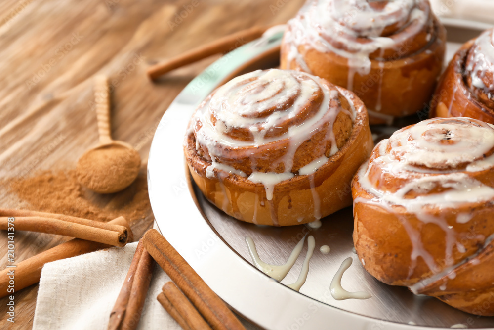 Plate with tasty cinnamon buns on wooden table, closeup Plate with tasty cinnamon buns on wooden table, closeup