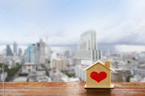 miniature house on wooden mock up over blurred top view of city on day noon light.Image for property real estate investment concept. 