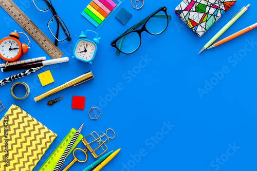 Education concept. Stationery frame with glasses and notebook on blue background top view copy space