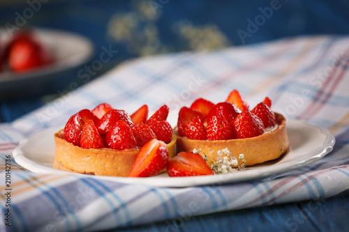 Tasty tartlets with strawberries on table photo