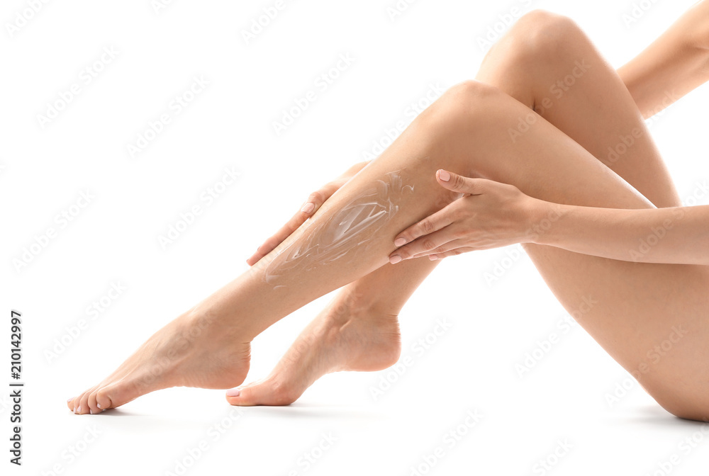 Young woman applying cream onto her leg after depilation on white background Young woman applying cream onto her leg after depilation on white background