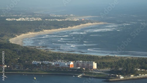 Top view of a beautiful sandy beach with the blue waves rolling into the shore, some rocks present. Portugal