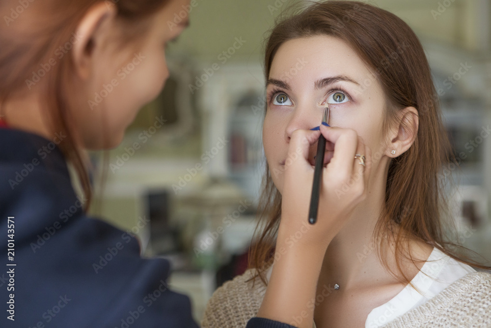 Brunette make up artist woman applying make up for a caucasian brunette bride, preparing her for a wedding photosession or a date Brunette make up artist woman applying make up for a caucasian brunette bride, preparing her for a wedding photosession or a date
