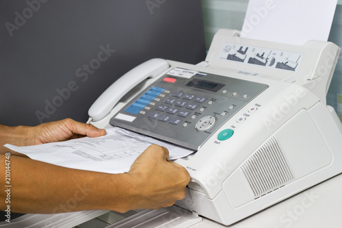 hand man are using a fax machine in the office. Business concept  photo