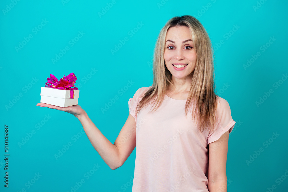 cheerful attractive woman smiling and holding a box with a gift on a blue background in the studio. cheerful attractive woman smiling and holding a box with a gift on a blue background in the studio.
