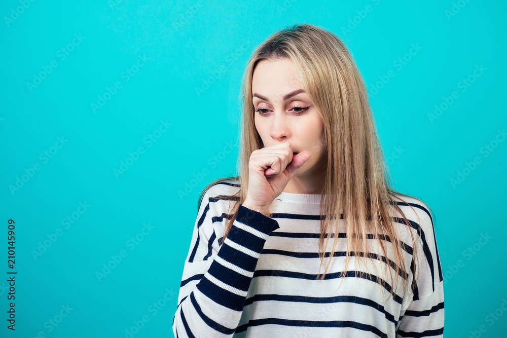 portrait of a young attractive sick female person with blonde hair and makeup cough and sneeze in the studio on a blue background. the concept of cold and allergens portrait of a young attractive sick female person with blonde hair and makeup cough and sneeze in the studio on a blue background. the concept of cold and allergens