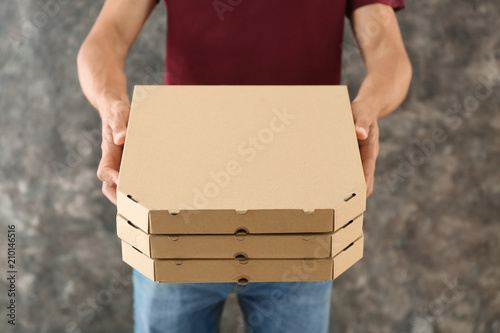 Young man with pizza boxes on grunge background. Food delivery service © Pixel-Shot