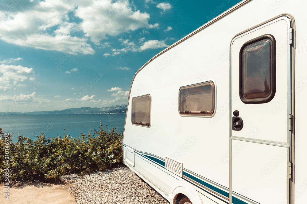 Caravan Trailer Near Sea, Beach And Blue Sky. Summer Holidays Road Trip Travel Concept - obrazy, fototapety, plakaty 