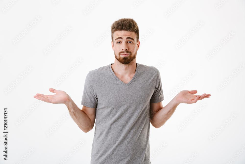 Confused young man standing isolated over white wall Confused young man standing isolated over white wall