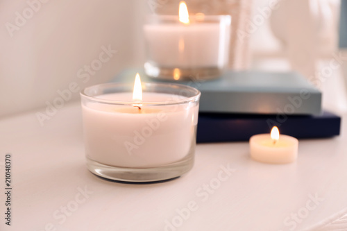 Burning wax candles on table