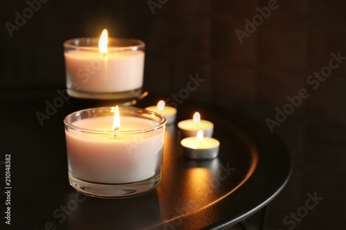 Burning wax candles on table in darkness