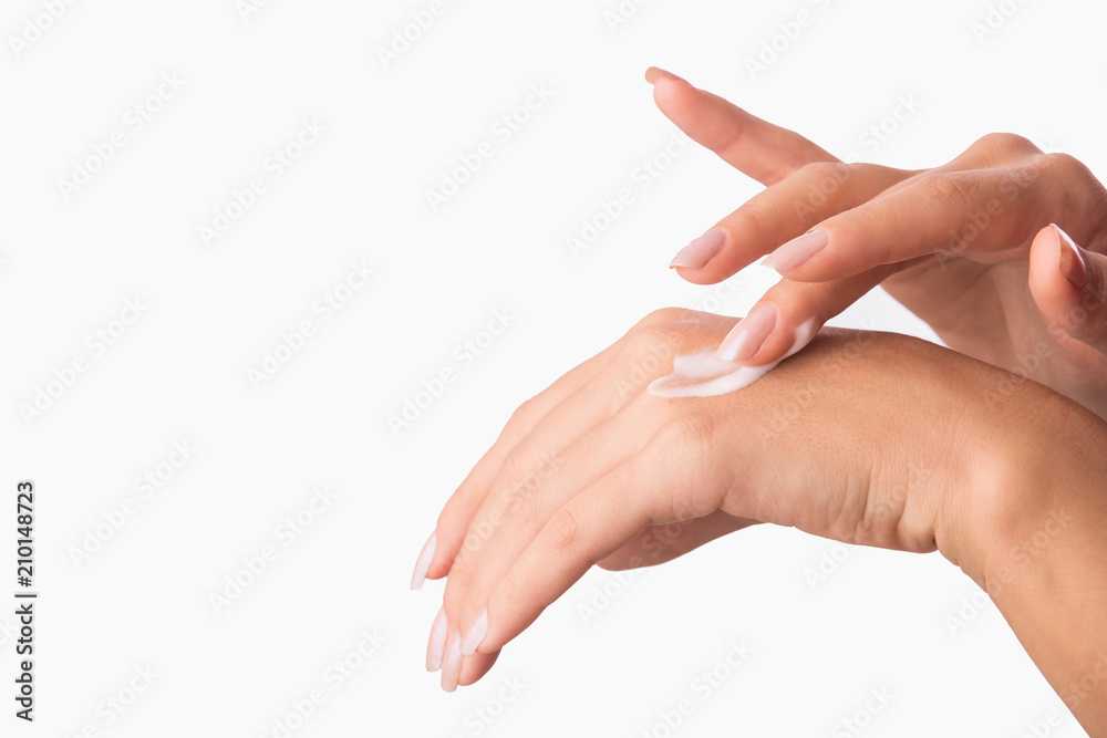 Hand skin care. Closeup of woman hands applying cream for hands isolated on white