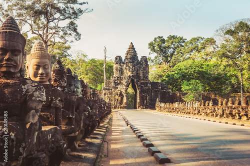 Row of sculptures in the South Gate of Angkor Thom complex. Siem Reap, Cambodia.Angkor wat in the rays of the setting sun.Angkor Thom is a popular tourist attraction.