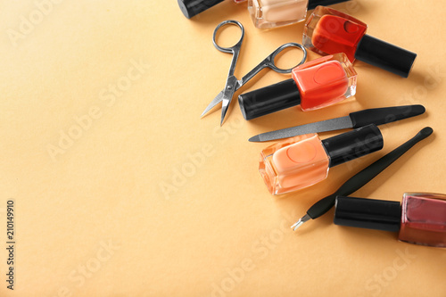 Bottles of nail polishes and tools for manicure on color background