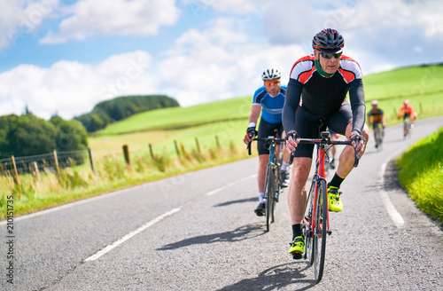 Cyclists racing on country roads on a sunny day in the UK.