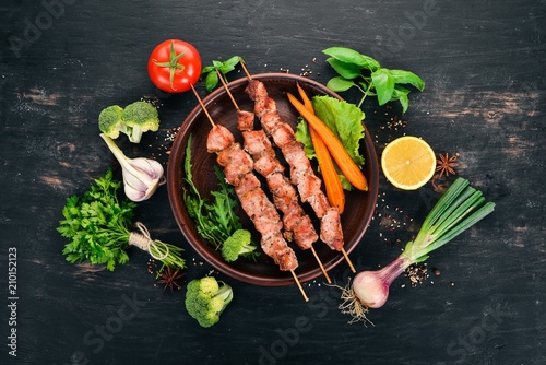 Baked Skewers of meat on a plate. On a wooden background. Top view. Copy space.