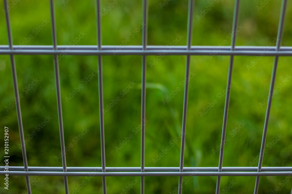 metal fence on green unfocused background concept with empty space for copy or text
