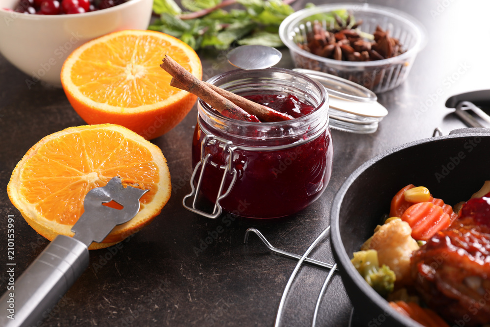 Jar with delicious cranberry sauce and products on table