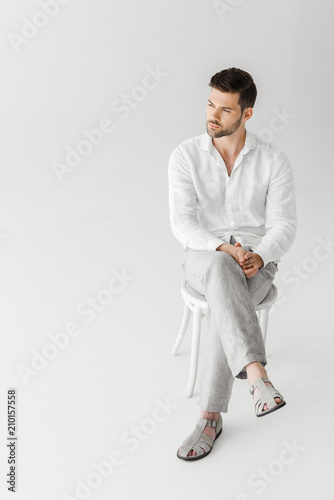 man in linen clothes sitting on chair isolated on grey background